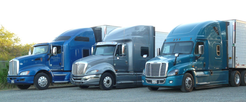three blue trucks with trailers lined up